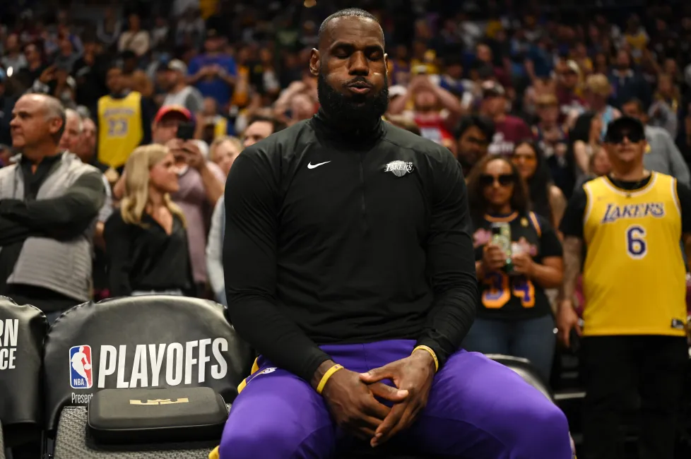LeBron James sitting courtside with his eyes closed before a game.